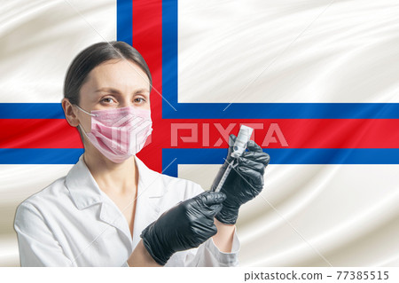 Girl doctor prepares vaccination against the background of the Faroe Islands flag. Vaccination concept Faroe Islands Girl doctor prepares vaccination against the background of the Faroe Islands flag. Vaccination concept Faroe Islands 77385515