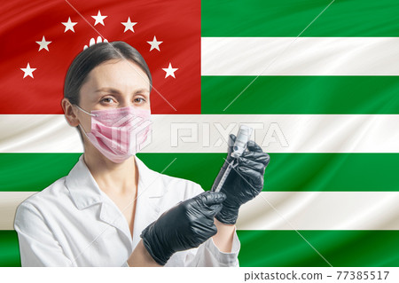 Girl doctor prepares vaccination against the background of the Abkhazia flag. Vaccination concept Abkhazia Girl doctor prepares vaccination against the background of the Abkhazia flag. Vaccination concept Abkhazia 77385517