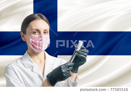 Girl doctor prepares vaccination against the background of the Finland flag. Vaccination concept Finland 77385528