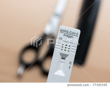Testing Before Visiting The Hairdresser: Rapid Antigen Corona Test Showing A Negative Result In Front of Scissors and Comb 77385595