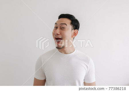 Funny grin smile face of man in white t-shirt isolated on white wall. Funny grin smile face of man in white t-shirt isolated on white wall. 77386218