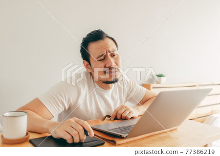 Serious man is working in his apartment in concept of Work From Home. Serious man is working in his apartment in concept of Work From Home. 77386219