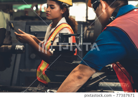 Group of skillful workers using machine equipment in factory workshop Group of skillful workers using machine equipment in factory workshop 77387671