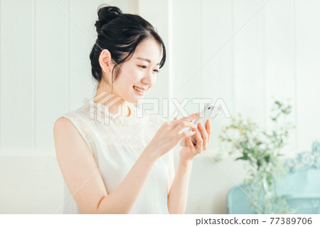 女人看著智能手機（微笑） 77389706