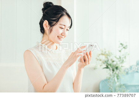 女人看著智能手機（微笑） 77389707