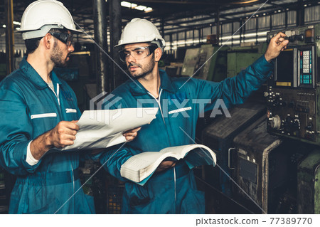 Group of skillful factory workers using machine equipment in workshop Group of skillful factory workers using machine equipment in workshop 77389770