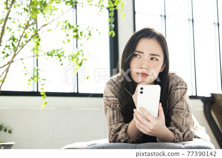 在智能手機上搜索的年輕女性擔心 在智能手機上搜索的年輕女性擔心 77390142