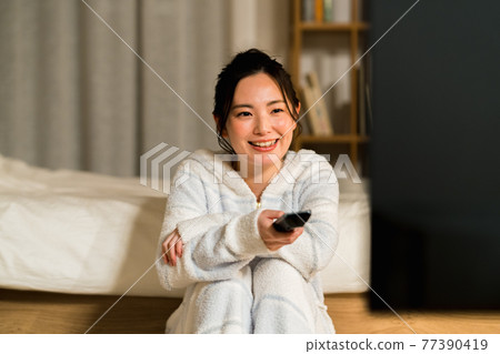 A young lady watching TV in the living room 77390419