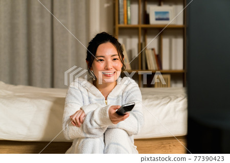 A young lady watching TV in the living room A young lady watching TV in the living room 77390423