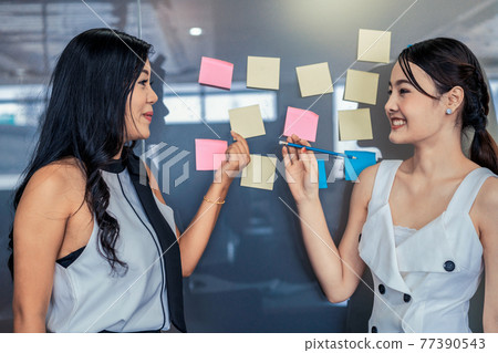 Two businesswomen talk and discuss creative idea. Two businesswomen talk and discuss creative idea. 77390543