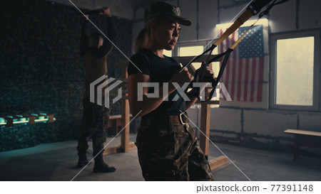 Female soldier doing TRX lunge near squadmate 77391148