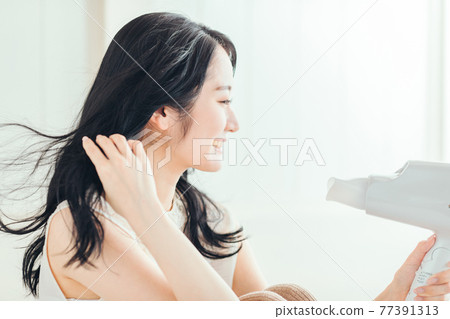 一個女人用吹風機 77391313