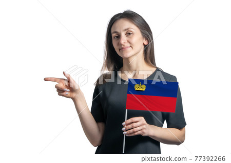 Happy young white woman holding flag Liechtenstein and points to the left isolated on a white background Happy young white woman holding flag Liechtenstein and points to the left isolated on a white background 77392266