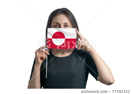 Happy young white woman holding flag Greenland flag and covers her face with it isolated on a white background Happy young white woman holding flag Greenland flag and covers her face with it isolated on a white background 77392332