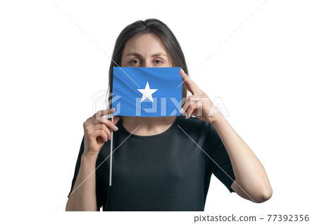 Happy young white woman holding flag Somalia flag and covers her face with it isolated on a white background 77392356