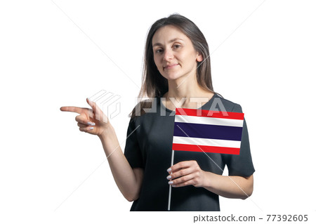 Happy young white woman holding flag Thailand and points to the left isolated on a white background 77392605