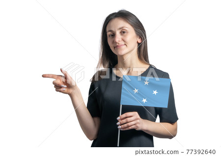 Happy young white woman holding flag Federated States of Micronesia and points to the left isolated on a white background Happy young white woman holding flag Federated States of Micronesia and points to the left isolated on a white background 77392640