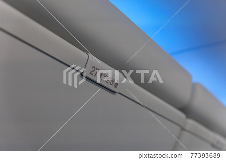 Sign of seat number with number and letter on luggage shell inside passenger airplane Sign of seat number with number and letter on luggage shell inside passenger airplane 77393689