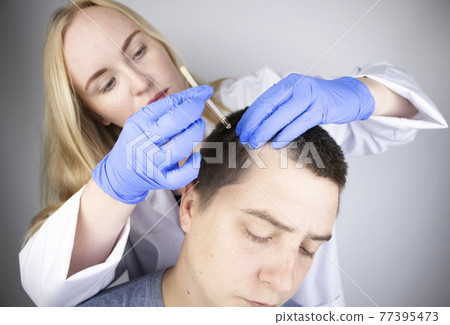 A trichologist doctor drips the serum onto the patient's hair. Treatment of alopecia. Hair loss, alopecia, pruritus, burning head or seborrhea 77395473