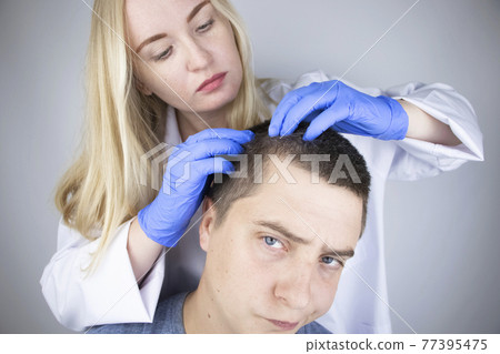 A trichologist examines the hair of a man who begins alopecia. Consultation with a dermatologist. Hair loss, alopecia, pruritus, burning head or seborrhea 77395475