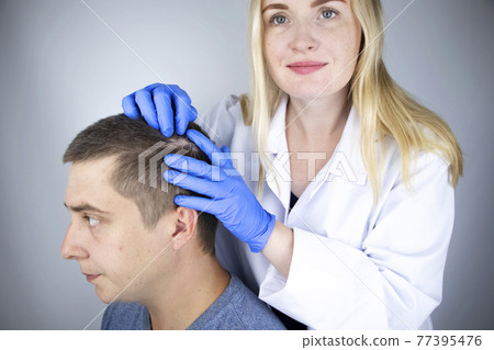 A trichologist examines the hair of a man who begins alopecia. Consultation with a dermatologist. Hair loss, alopecia, pruritus, burning head or seborrhea 77395476