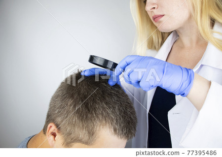 A trichologist examines the hair of a man who begins alopecia. Consultation with a dermatologist. Hair loss, alopecia, pruritus, burning head or seborrhea 77395486