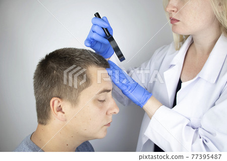 A trichologist examines the hair of a man who begins alopecia. Consultation with a dermatologist. Hair loss, alopecia, pruritus, burning head or seborrhea 77395487