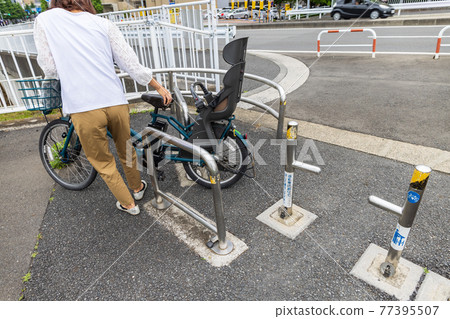一名婦女推著自行車穿過安裝在自行車專用道路上的圍欄，以防止汽車和摩托車進入 77395507