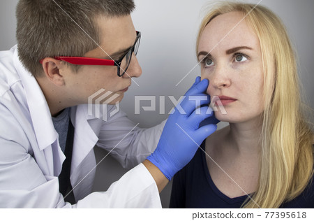 An ophthalmologist examines a woman who complains of a burning sensation and pain in her eyes. Eye fatigue from a computer screen or telephone (sand sensation on the cornea). The concept of early 77395618