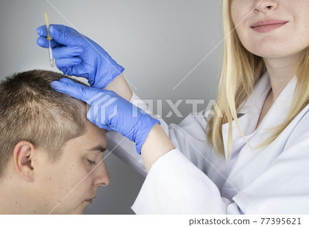 A trichologist doctor drips the serum onto the patient's hair. Treatment of alopecia. Hair loss, alopecia, pruritus, burning head or seborrhea 77395621