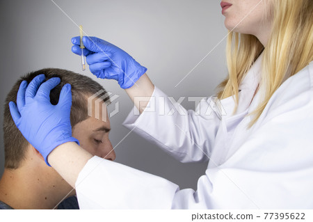 A trichologist doctor drips the serum onto the patient's hair. Treatment of alopecia. Hair loss, alopecia, pruritus, burning head or seborrhea A trichologist doctor drips the serum onto the patient's hair. Treatment of alopecia. Hair loss, alopecia, pruritus, burning head or seborrhea 77395622