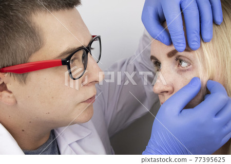 An ophthalmologist examines a woman who complains of a burning sensation and pain in her eyes. Eye fatigue from a computer screen or telephone (sand sensation on the cornea). The concept of early 77395625
