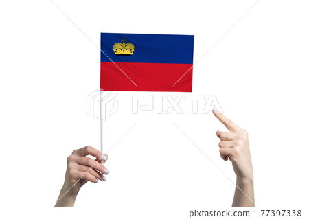 A beautiful female hand holds a Liechtenstein flag to which she shows the finger of her other hand, isolated on white background A beautiful female hand holds a Liechtenstein flag to which she shows the finger of her other hand, isolated on white background 77397338