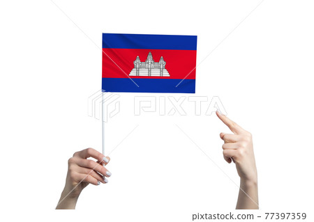 A beautiful female hand holds a Cambodia flag to which she shows the finger of her other hand, isolated on white background A beautiful female hand holds a Cambodia flag to which she shows the finger of her other hand, isolated on white background 77397359