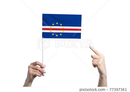A beautiful female hand holds a Cape Verde flag to which she shows the finger of her other hand, isolated on white background A beautiful female hand holds a Cape Verde flag to which she shows the finger of her other hand, isolated on white background 77397361