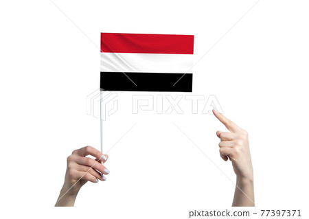A beautiful female hand holds a Yemen flag to which she shows the finger of her other hand, isolated on white background 77397371