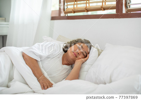 Asian Elderly woman with white hairs close eyes smile sleep and sweet dream on bed in cozy bedroom in the morning feeling so relax and comfortable,Healthcare and Sleep Concept 77397869