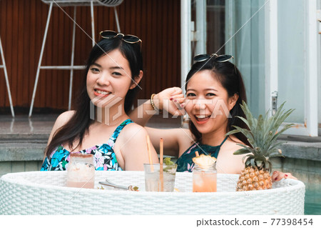 Two pretty Asian women eating breakfast in the pool, floating breakfast. 77398454