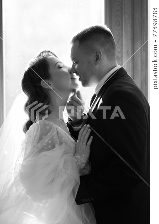 silhouettes of the bride and groom in sunlight through the glass in the door. 77398783