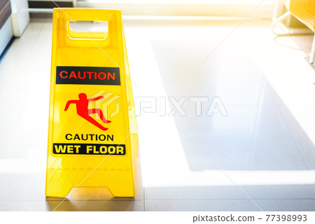 Sign showing warning of caution wet floor on wet tile floor in department store 77398993
