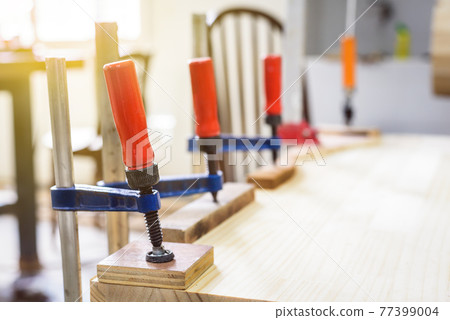 Clamped pieces of wood with c-clamps and bar clamp , wooden parts in the carpentry workshop Clamped pieces of wood with c-clamps and bar clamp , wooden parts in the carpentry workshop 77399004