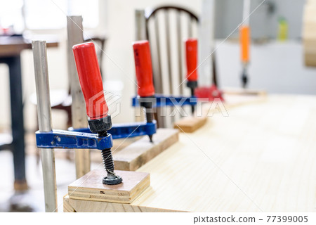 Clamped pieces of wood with c-clamps and bar clamp , wooden parts in the carpentry workshop 77399005