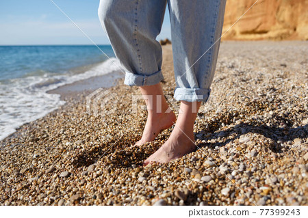close-up photo. bare feet in tucked up jeans on the sand close-up photo. bare feet in tucked up jeans on the sand 77399243