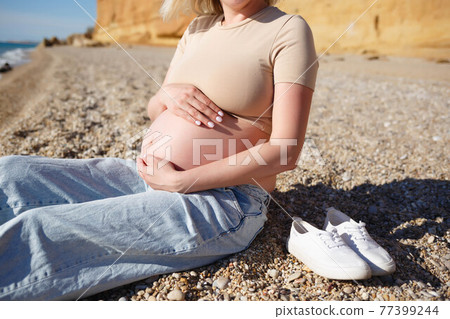 close-up photo. a pregnant woman sits on the seashore close-up photo. a pregnant woman sits on the seashore 77399244