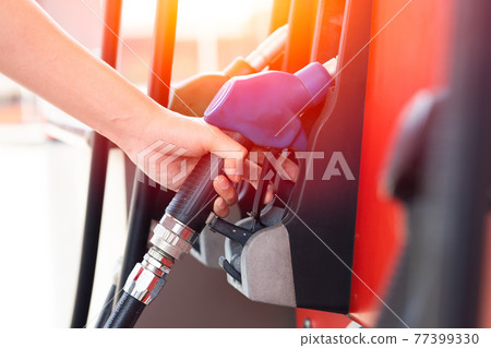 Worker hand at Gas station handle fuel nozzle at fuel dispensers for filling car engine gasoline 77399330