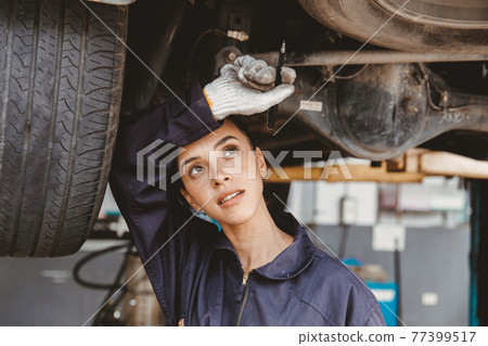 Tired woman staff worker hard work in hot danger place wiping away sweat working in auto car service garage. Tired woman staff worker hard work in hot danger place wiping away sweat working in auto car service garage. 77399517