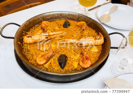 Delicious traditional Valencian seafood paella (savory rice dish with shrimps, squid and clams) Delicious traditional Valencian seafood paella (savory rice dish with shrimps, squid and clams) 77399947