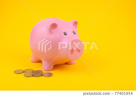 pink piggy bank on a yellow background with lying coins 77401954