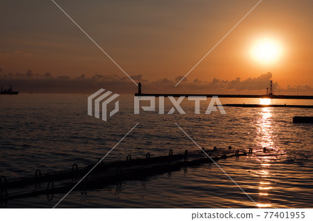 orange sunset in the port on the background of the lighthouse and the sea orange sunset in the port on the background of the lighthouse and the sea 77401955