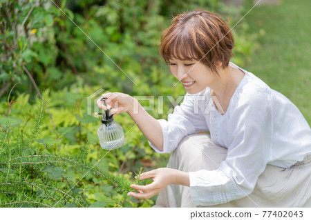 A young woman gardening who cares for plants in the garden 77402043
